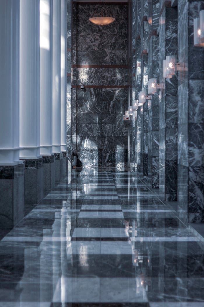 Sleek modern hallway featuring marble walls and floor with reflective surfaces and soft lighting.